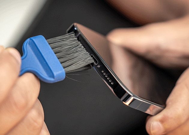 Cleaning iPhone charging port with a soft brush.